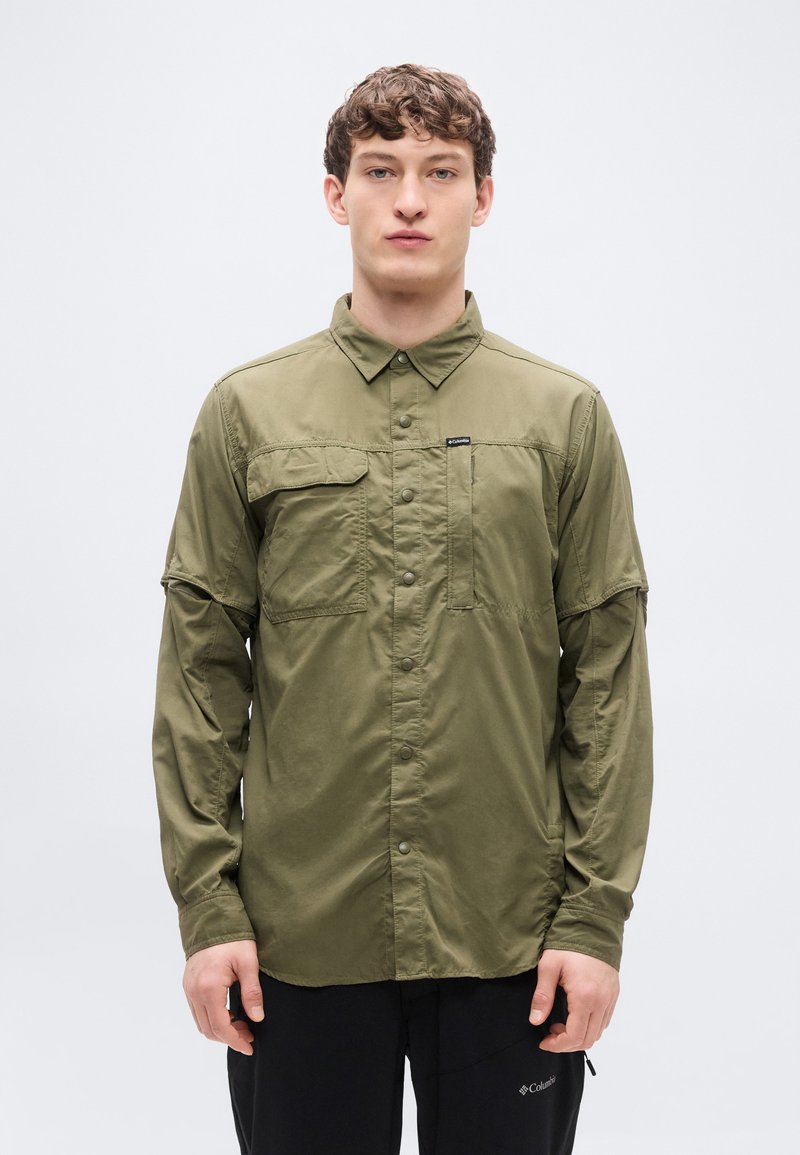 Μακρυμάνικο πουκάμισο ελιάς με κουμπιά μπροστά, δύο τσέπες στο στήθος και κανονικό γιακά. Κατασκευασμένο από ελαφρύ, λείο ύφασμα.