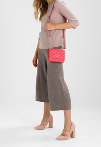 Světlá růžová halenka s tříčtvrtečními rukávy, šedé žebrované culottes, růžová prošívaná crossbody taška a světle růžové boty na blokovém podpatku.