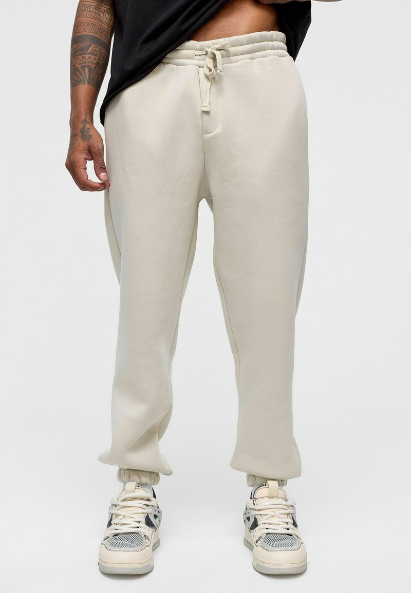 Crème-kleurige sweatpants van zacht materiaal, met een elastische tailleband met trekkoord, taps toelopende manchetten en zijzakken.