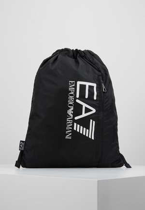 Sac à cordon noir avec logo EA7 Emporio Armani blanc, placé sur une surface blanche sur un fond clair uni.