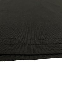 Schwarzer rippierter Stoff mit glatter Textur, der zwei gefaltete Lagen zeigt und entlang der Kante eine saubere Naht aufweist.