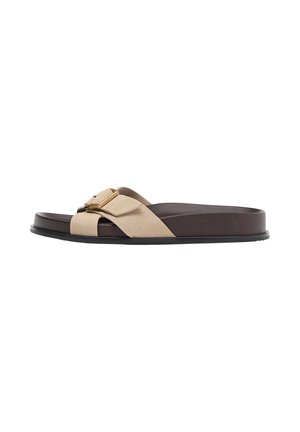 Sandale slide marron avec une lanière en daim beige croisée et une boucle dorée sur une semelle plate noire.