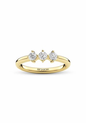 Guld ring med tre runde diamanter sat på række øverst, indgraveret med mærkenavnet Sif Jakobs inde i ringen.