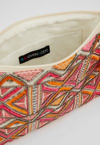 Pochette brodée avec des motifs géométriques en rose, orange et argent, dotée d'un intérieur de couleur crème et d'une étiquette de marque.