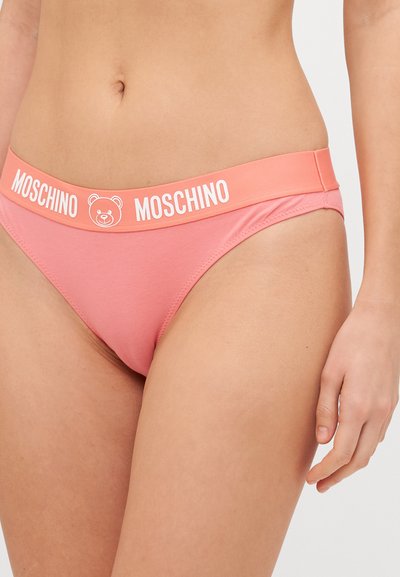 Gaiši rozā bikini apakšdaļa ar platām, markētām jostām, kurā ir neveiksmīgā lāča logo. Gluda auduma un klasiskā zema jostasvieta.