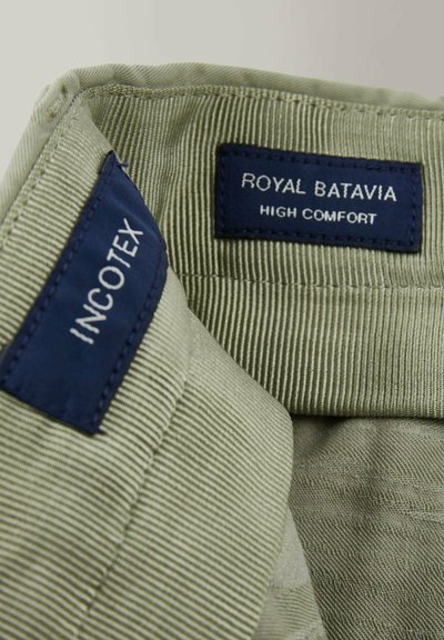 Groen corduroy-stof met een geribbelde textuur. Labels lezen "INCOTEX" en "ROYAL BATAVIA HIGH COMFORT" in donkerblauw.