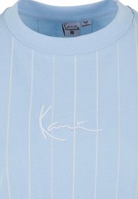 Hellblaues T-Shirt mit vertikalen weißen Streifen. Rundhalsausschnitt, weicher Stoff, mit gesticktem Logo in Weiß auf der Vorderseite. Größe M.