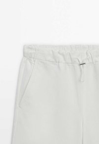 Lichtgrijze joggingsbroek met een elastische tailleband, koord en zijzakken. Zachte stof met een gladde textuur en geen zichtbare patronen.