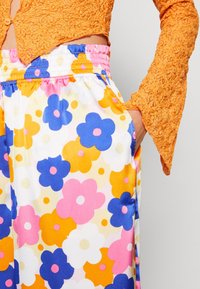 Pantalones con estampado floral en tejido ligero con una cinturilla elástica. Los colores incluyen rosa, azul, naranja y amarillo. Cuenta con bolsillos laterales.