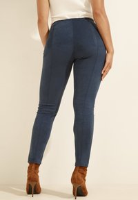 Modré legíny s vysokým pasem vyrobené z měkkého a elastického materiálu s hladkým povrchem. Mají elegantní design a úzký střih.