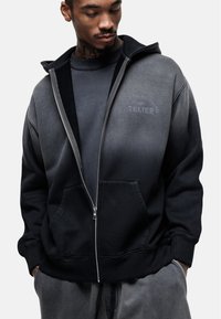 Felpa zip con cappuccio nera e grigia, dal tatto morbido, dotata di una tasca frontale, cappuccio e un logo stampato discreto sul petto.