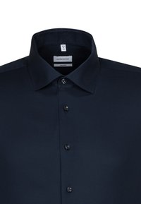 Camicia da uomo blu navy in tessuto tela, con colletto a punta, chiusura frontale a sei bottoni e piccole etichette. Tessuto liscio, design strutturato e vestibilità sagomata.