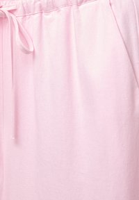 Pantalons de jogging rose clair fabriqués en tissu doux et texturé, avec une taille élastique et un cordon de serrage. Comprend des poches latérales.