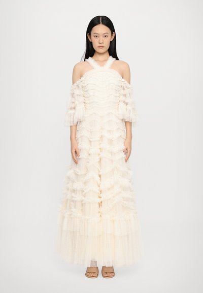 Robe longue, à épaules dénudées, en tulle crème clair avec des volants superposés et un motif texturé, présentant des manches transparentes et bouffantes.