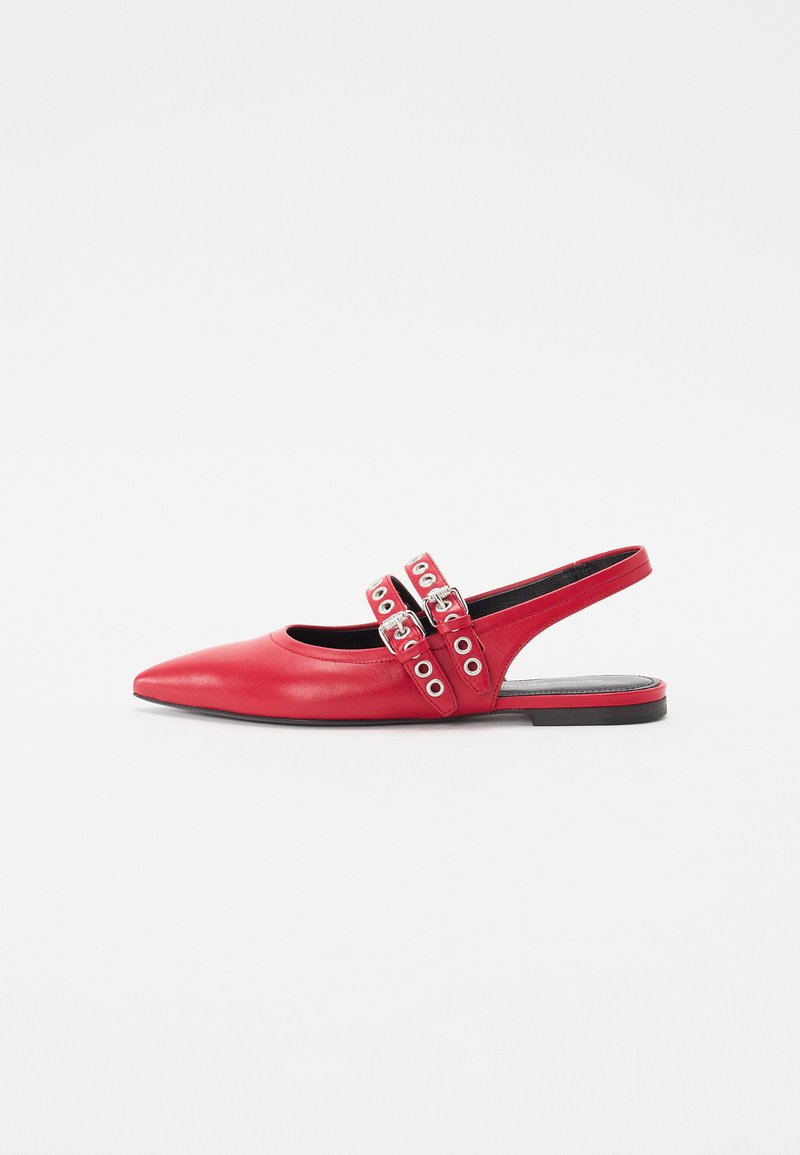 Scarpa slingback in pelle rossa con punta affilata, due cinturini con fibbie decorati con borchie, e suola piatta. Texture liscia e design minimalista.