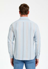 Camicia a righe blu chiaro con pattern verticali, colletto button-down e maniche lunghe; presenta sottili dettagli testurizzati e un design aderente.