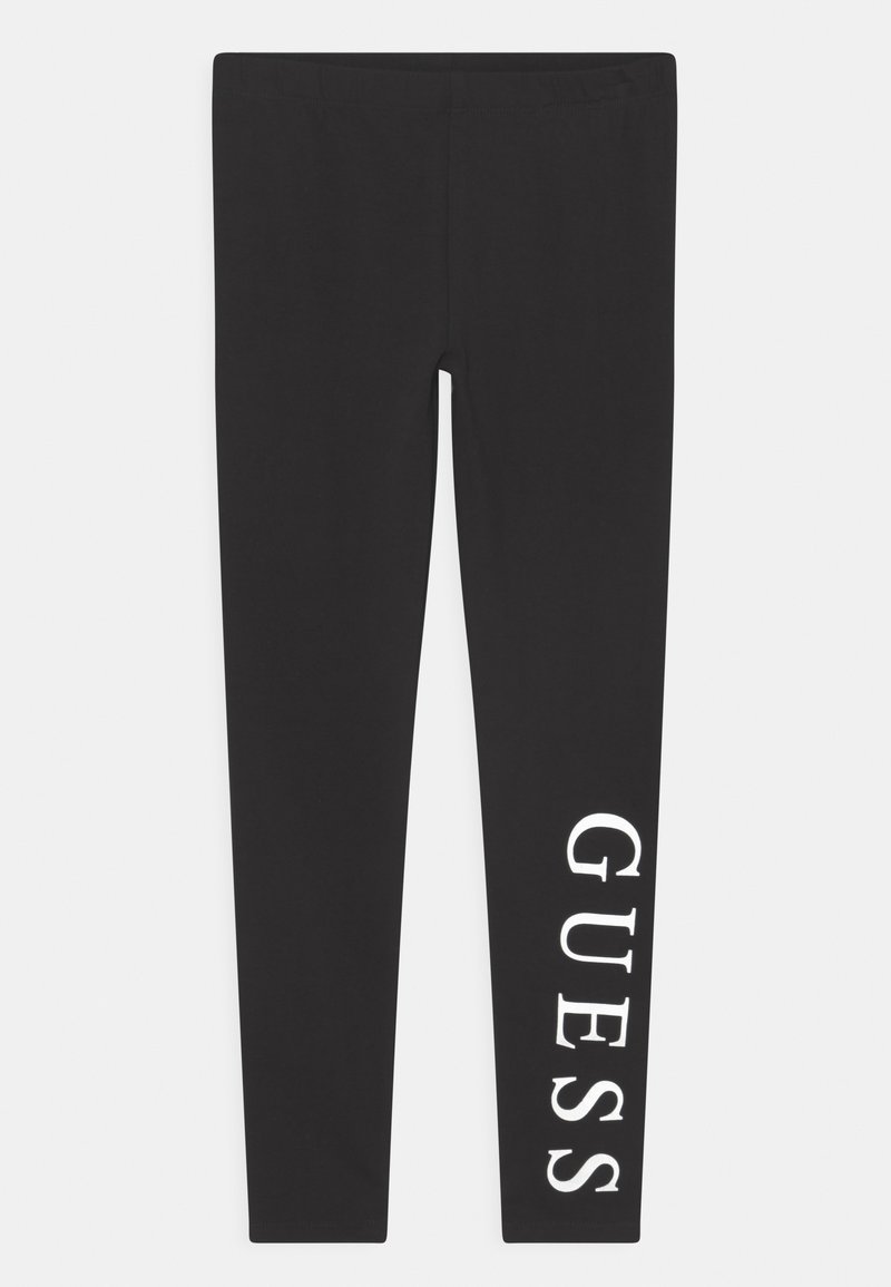 Zwarte leggings van rekbaar materiaal, met een witte "GUESS" logo dat verticaal op het linkerbeen is gedrukt. Glad materiaal, aansluitend ontwerp.