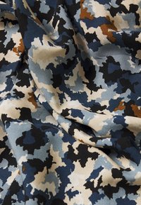 Tela de patrón de camuflaje que presenta tonos de azul, negro, blanco y marrón. La textura parece suave con un caído blando.