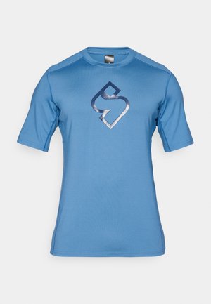 Blauwe sportieve korte mouwen shirt van gladde stof, met een donkerblauw logo in het midden. Naadloos schouderontwerp met ronde halslijn.