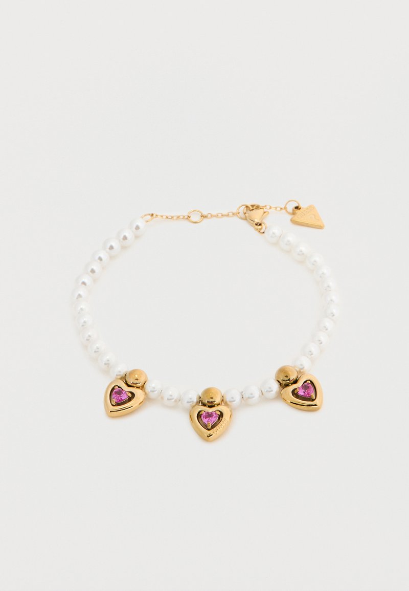 Βραχιόλι με πέρλες που φέρει τρία χρυσά καρδιακά κρεμαστά με ρόδινες πολύτιμες πέτρες. Ο σχεδιασμός περιλαμβάνει λείες στρογγυλές πέρλες και μια λεπτή χρυσή αλυσίδα.