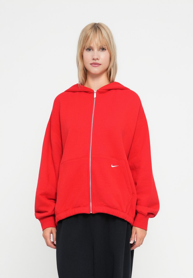 Felpa rossa con zip realizzata in morbido misto cotone, dotata di tasca frontale e accento con logo bianco. Presenta un fit rilassato e un ampio cappuccio.
