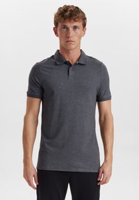 Tmavě šedé polo tričko vyrobené z měkké látky, s tříknoflíkovým zapínáním a krátkými rukávy. Minimalistický design s diskrétním logem.