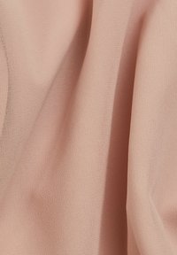 Ljust rosa tyg med en mjuk, texturerad yta som draperar sig graciöst. Har en fin väv som framhäver ett slätt och känsligt utseende.