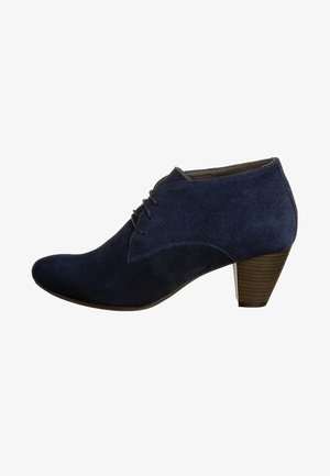 Botas de tobillo de ante azul marino con punta afilada, cordones en la parte delantera y tacón apilado. Presentan una textura suave y un sutil detalle de costura.