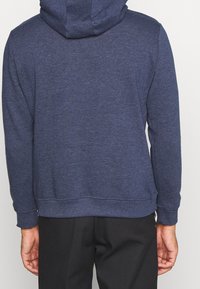 Námorně modrá mikina s kapucí vyrobená z měkké tkaniny, s žebrovanými manžetami a lemem. Design je jednoduchý, bez výrazných vzorů nebo akcentů.