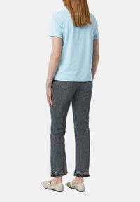 Lichtblauw t-shirt met korte mouwen, grijze spijkerbroek met zichtbare stiksels en beige mesh schoenen met veters. Casual pasvorm en rechte snit.