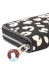 Czarny i kremowy portfel w panterkę z fakturowanej tkaniny, z metalowym zamkiem błyskawicznym i uchwytem w kształcie pączka w kolorze brązowym i niebieskim.