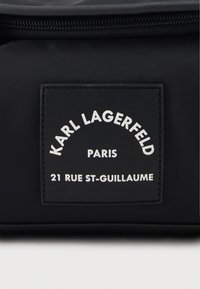 Black nylon bag featuring a rectangular black label with white text. Label displays "KARL LAGERFELD," "PARIS," and "21 RUE ST-GUILLAUME."