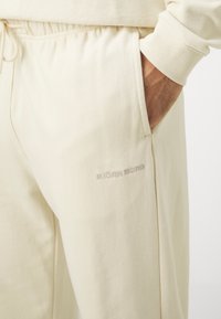 Krämfärgade joggerbyxor i mjuk bomull. Har elasticitet i midjan, sidofickor och diskret broderi av "BJÖRN BORG".