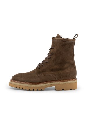 Stivale alla caviglia in suede marrone con lacci, suola in gomma tan e linguetta sul tallone, fotografato di lato su uno sfondo bianco.