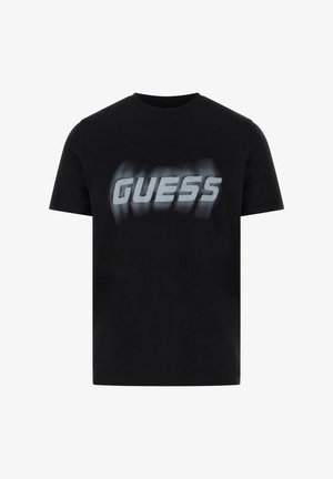 Mustast puuvillane t-särk lühikeste varrukatega, millel on suur, pleekinud valge "GUESS" logo trükitud rinna peale. Klassikaline ümar kaelus.