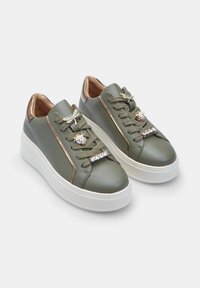 Olive green leather sneakers with a thick white sole, featuring decorative dragonfly and ladybug accents, and crystal embellishments on laces.