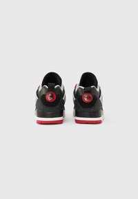 Melni un pelēki sporta apavi ar sarkanām detaļām, tajos ir teksturēts papēdis, mīkstināts apkakle un logotipa detaļa. Gumijas zolīte un viegli uzvelkamas cilpas.