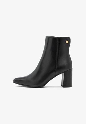 Czarne skórzane botki za kostkę z ciasnym noskiem i słupkowym obcasem. Charakteryzują się minimalistycznym designem z złotym akcentem po boku. Gładka faktura.