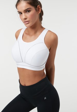 Soutien-gorge de sport blanc avec une finition texturée, des bonnets galbés et des accents gris subtils, associé à des leggings noirs taille haute.