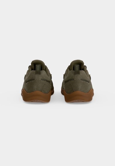Paire de baskets vert olive avec semelles marron, vues de dos sur un fond uni clair.