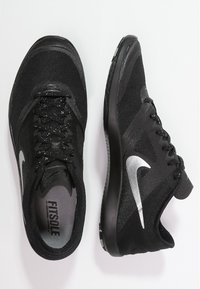 Scarpe da ginnastica nere con tomaia in mesh testurizzato, caratterizzate da uno swoosh Nike argentato, lacci neri e suola imbottita. Linee di design accentuate.