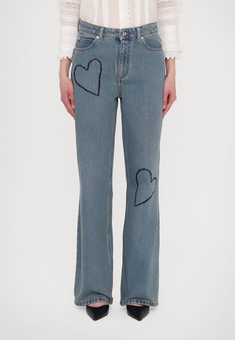Blauwe denim flared jeans met twee gestikte harten in zwart op de dijen. Heeft standaard zakken en een standaard tailleband.