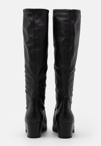Bottes noires en cuir montantes jusqu'aux genoux avec une texture lisse, un léger effet froncé et un talon bloc. Accents de coutures simples à l'arrière.
