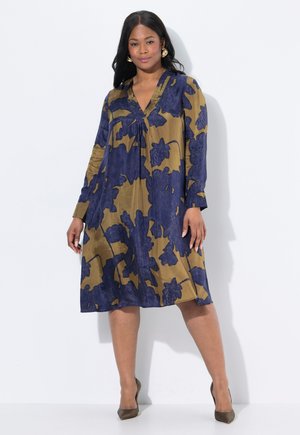 Vestido estampado con escote en v, mangas largas y silueta en A. La tela es de color verde oliva con grandes patrones florales en azul marino.