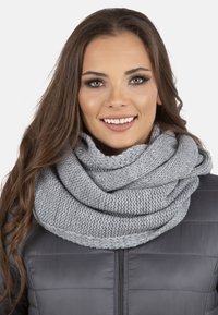 Grå strikket infinity-scarf med et tekstureret mønster, blødt draperet, båret over en sort puffjakke med en glat finish og lagdelt design.