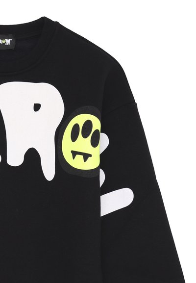 Felpa nera con grandi lettere bianche e un grafico di un fantasma sorridente verde neon con zanne. Tessuto morbido con un design casual.