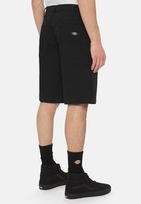 Sorte denimshorts med lige snit, med baglommer og et logo-patch. Båret med sorte strømper og ankelstøvler.