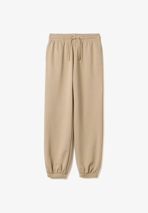 Beige joggingbroek met elastische tailleband en boorden, trekkoord en zijzakken, plat gelegd op een witte achtergrond.