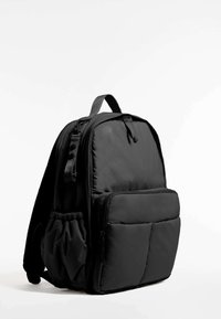 Crni jastučić torba s glatkom teksturom, koja ima odvojene dijelove sa zatvaračima, bočnu mrežastu džepu i podesive naramenice.