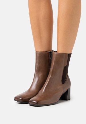 Brown leather ankle boots with a square toe, side zipper, and elastic panels. Features a medium block heel and smooth texture.